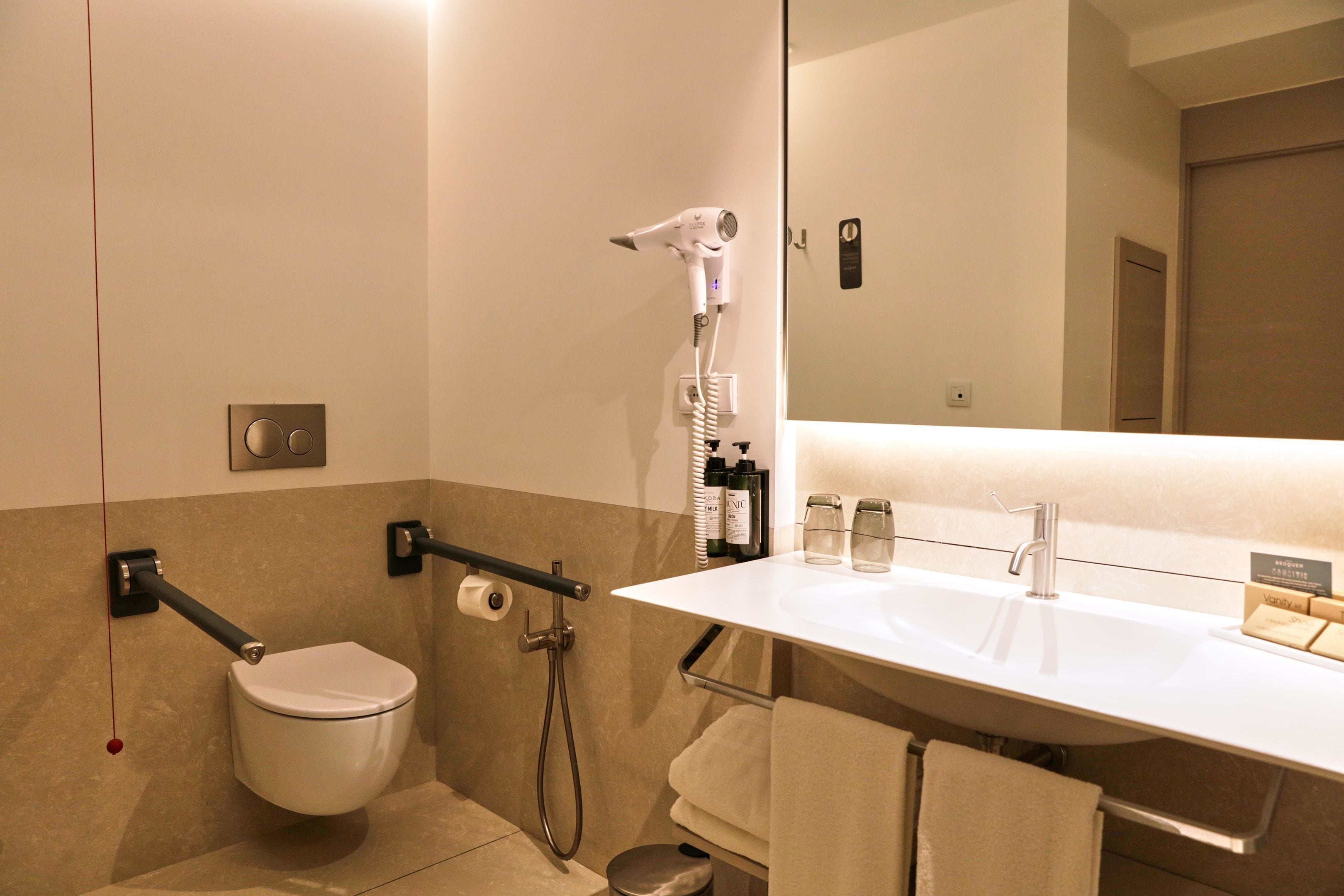 Un baño moderno con inodoro, ducha, lavabo y espejo.