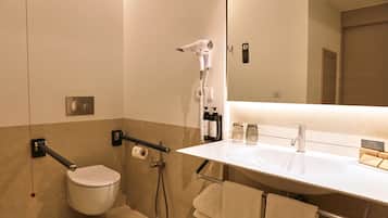 Un baño moderno con inodoro, ducha, lavabo y espejo.