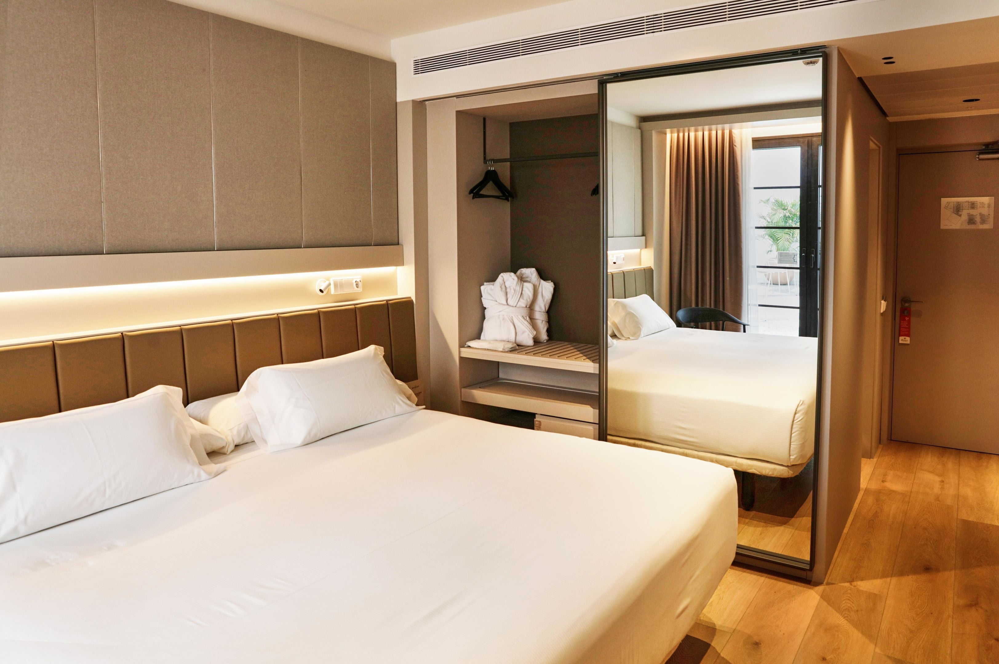 Ein Hotelzimmer mit einem großen Bett, einem begehbaren Kleiderschrank und einem Spiegel.