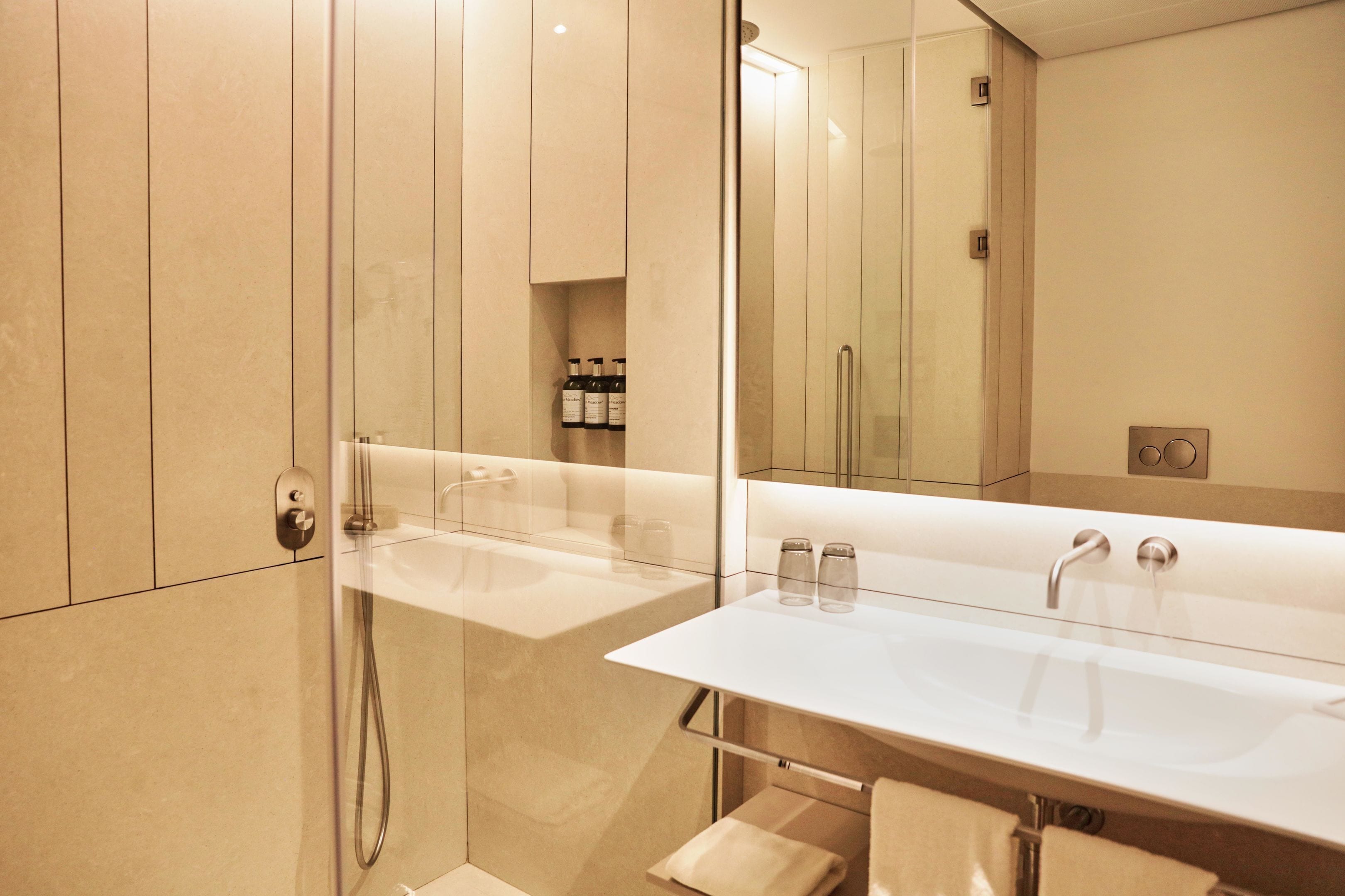 A modern bathroom with a glass-enclosed shower, a white sink, and a large mirror.