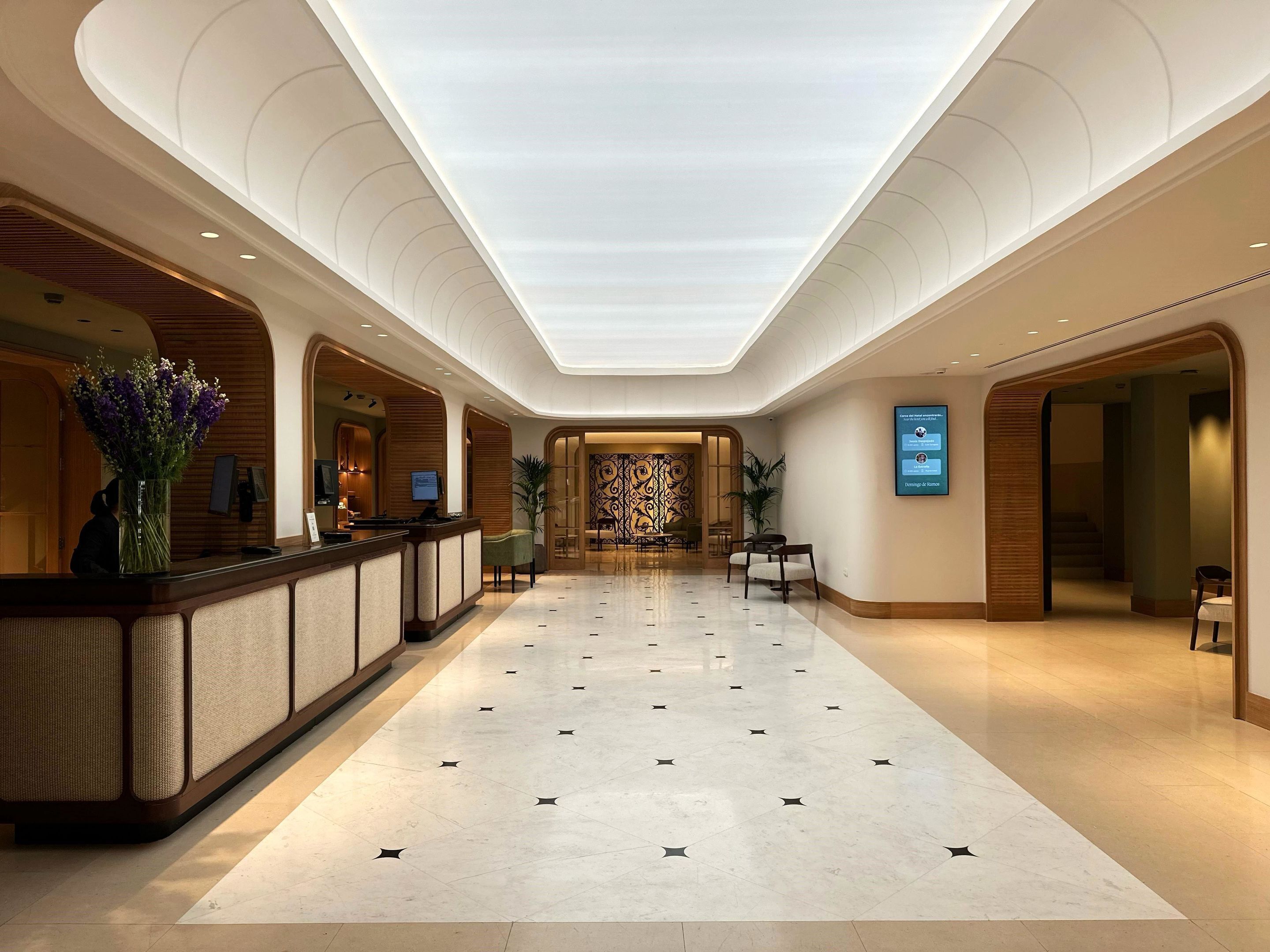 Un vestíbulo de hotel con mostrador de recepción, zona de estar y un diseño de pared con motivos.