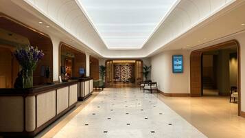 Un vestíbulo de hotel con mostrador de recepción, zona de estar y un diseño de pared con motivos.