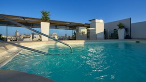 Une piscine sur le toit offrant une vue dégagée sur les toits de la ville, avec notamment une tour imposante bien visible.