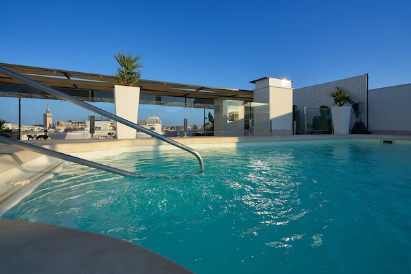 Una piscina al aire libre de temporada, sombrillas, tumbonas