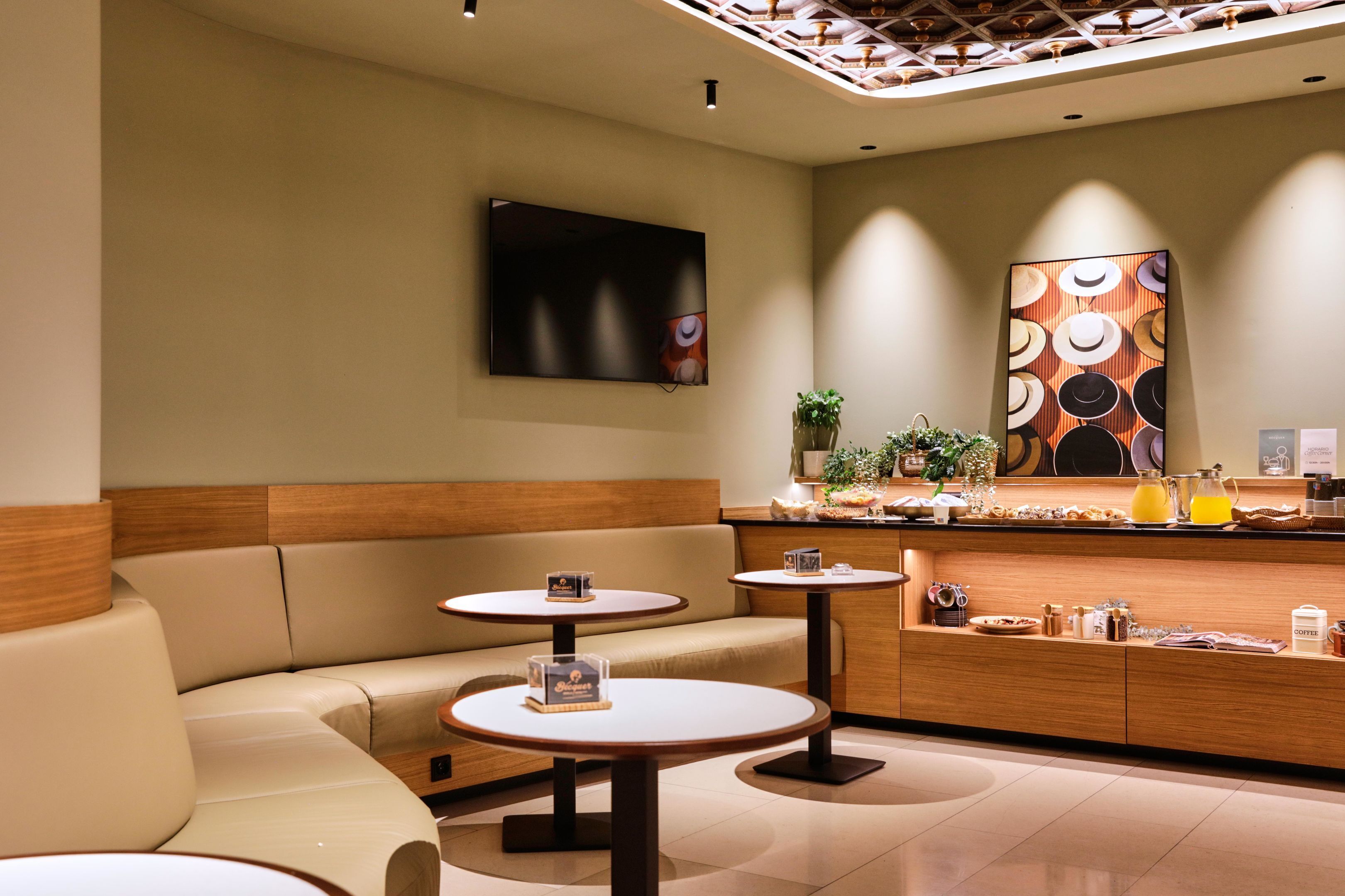 En modern hotellobby med en soffa, två runda bord, en receptionsdisk och konstverk på väggarna.