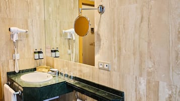 A bathroom with a sink, mirror, hairdryer, and towel rack.