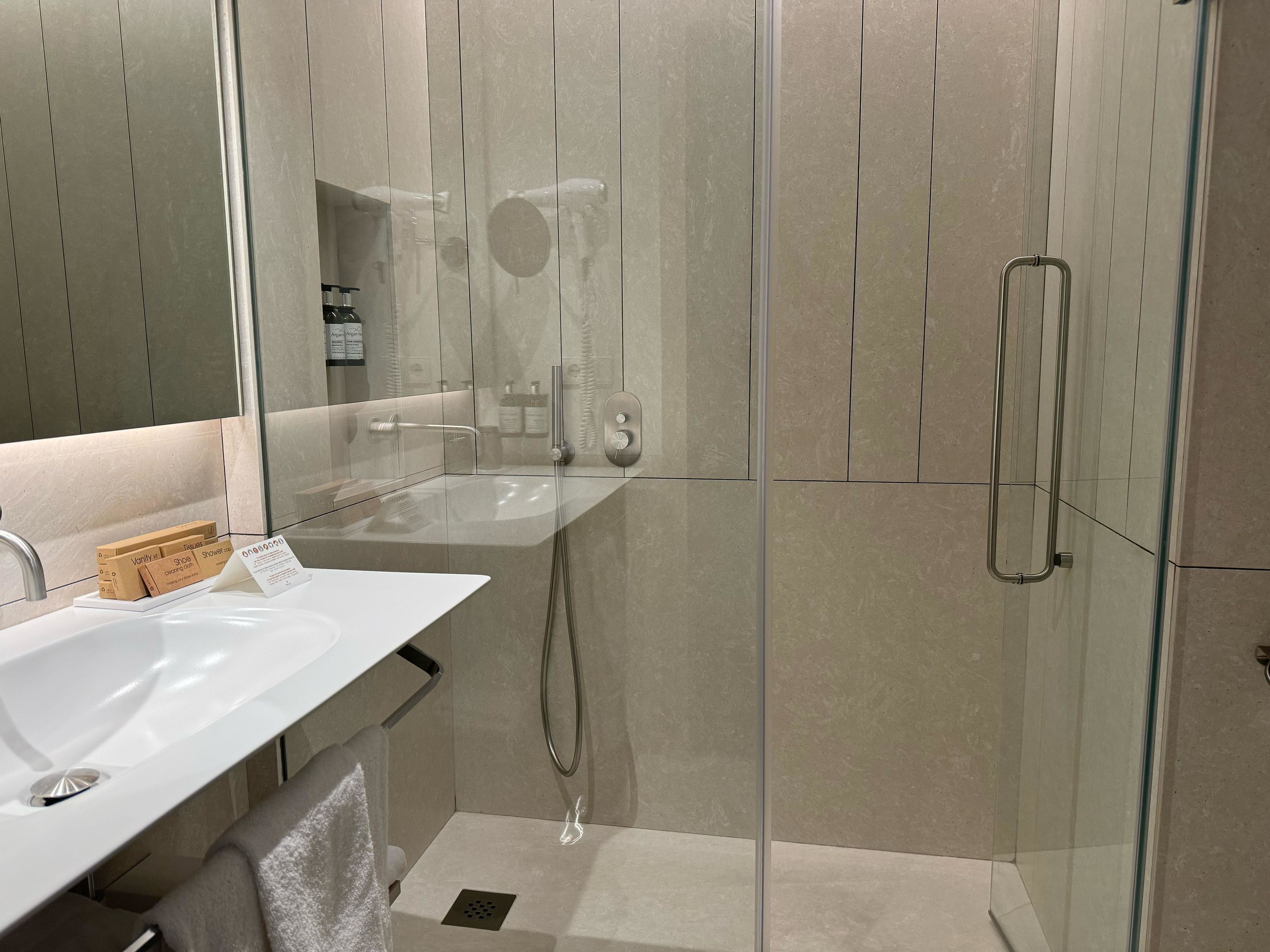 A modern bathroom with a glass-enclosed shower, a white sink, and a mirror.