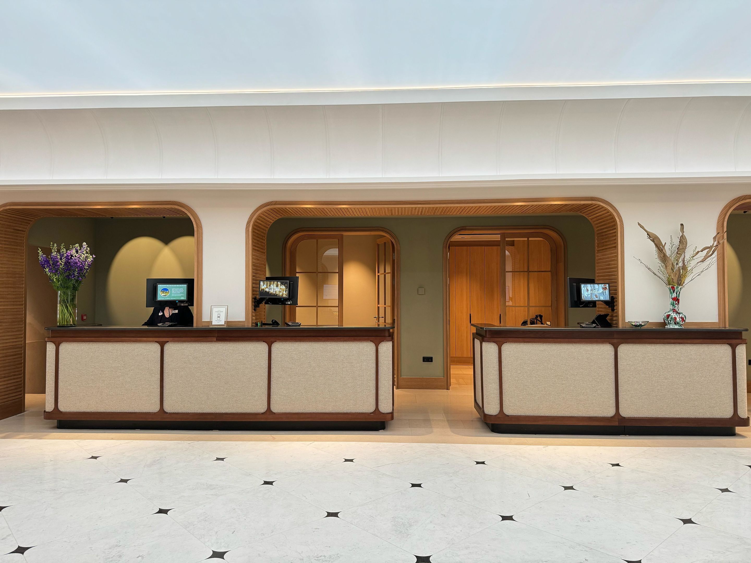 A reception area with two counters, each with a screen and a vase of dried plants.