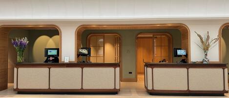 A reception area with two counters, each with a screen and a vase of dried plants.