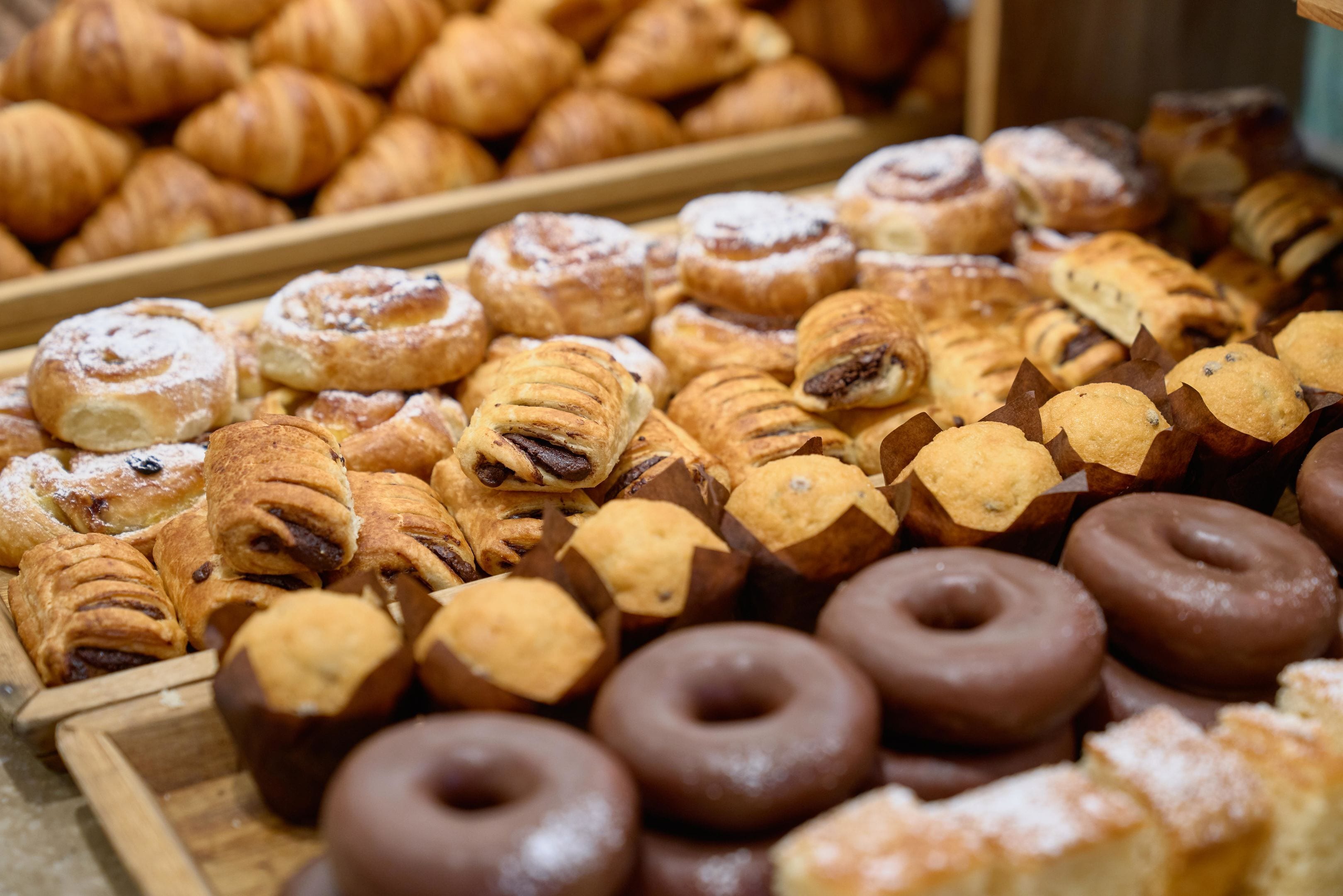 A variety of pastries including croissants, muffins, and chocolate donuts.