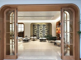 A modern interior with a wooden-framed entrance, a patterned wall, and a seating area with round tables and chairs.
