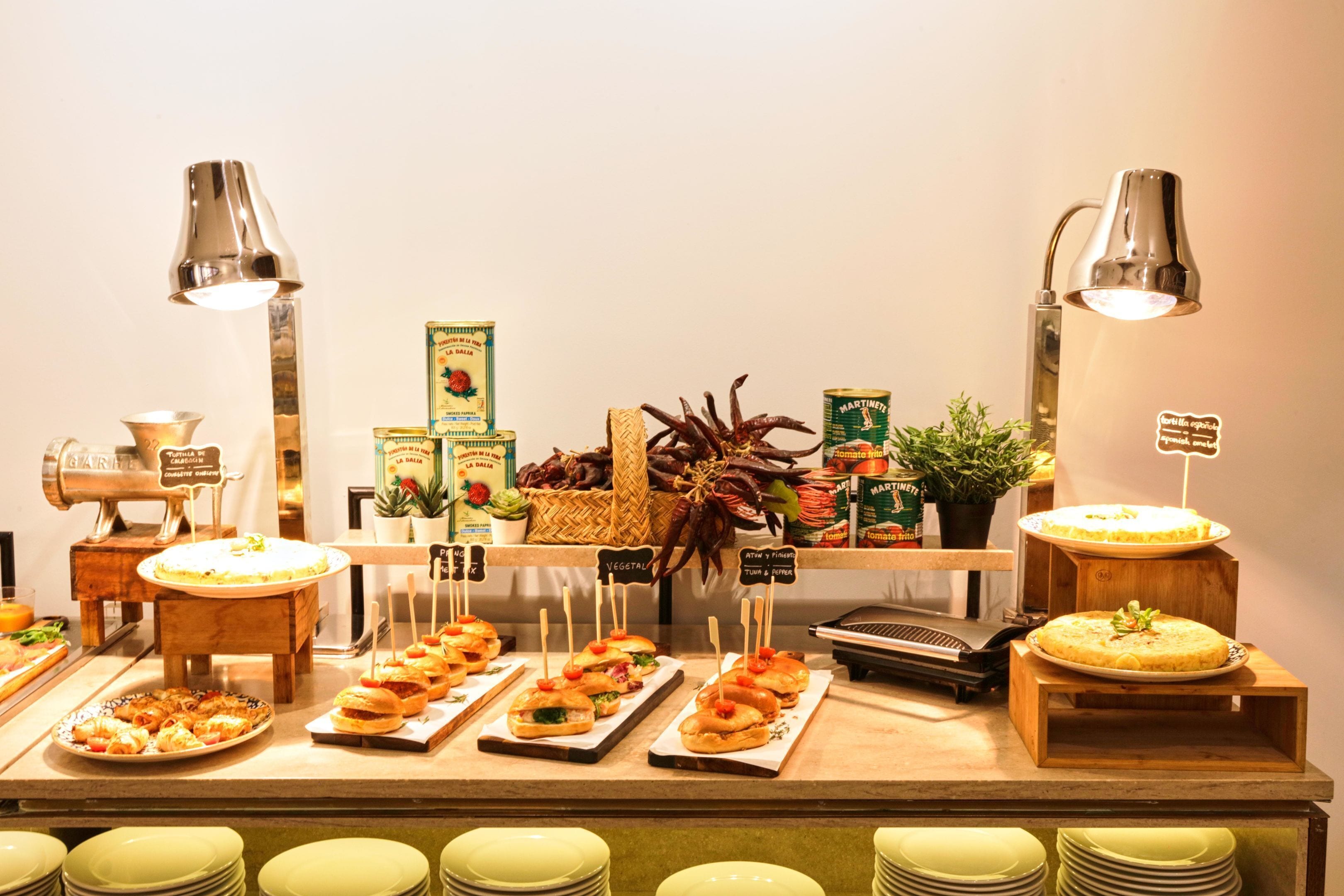 A buffet with various food items, including sandwiches, salads, and a cake, arranged on wooden stands with labels.