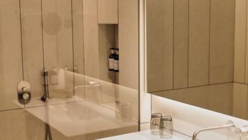 Un baño moderno con un espejo grande, un lavabo blanco y una zona de ducha.
