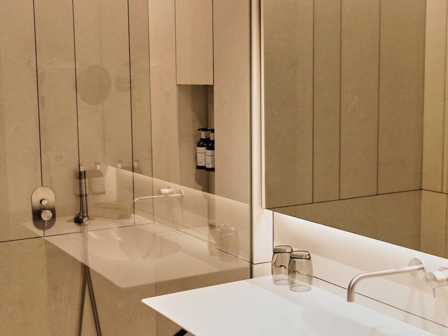 Un baño moderno con un espejo grande, un lavabo blanco y una zona de ducha.