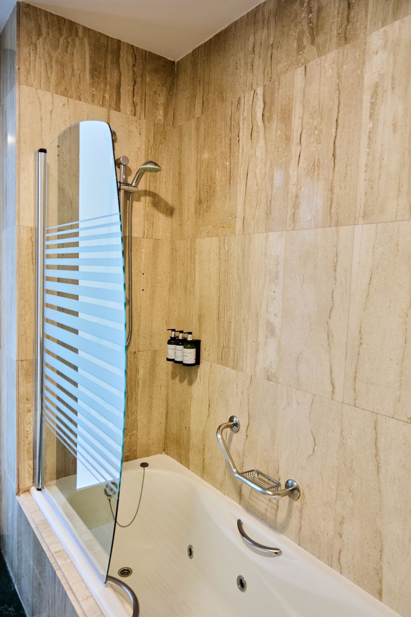 Een moderne badkamer met een badkuip, een glazen douchecabine en een wandhouder voor een wijnfles.