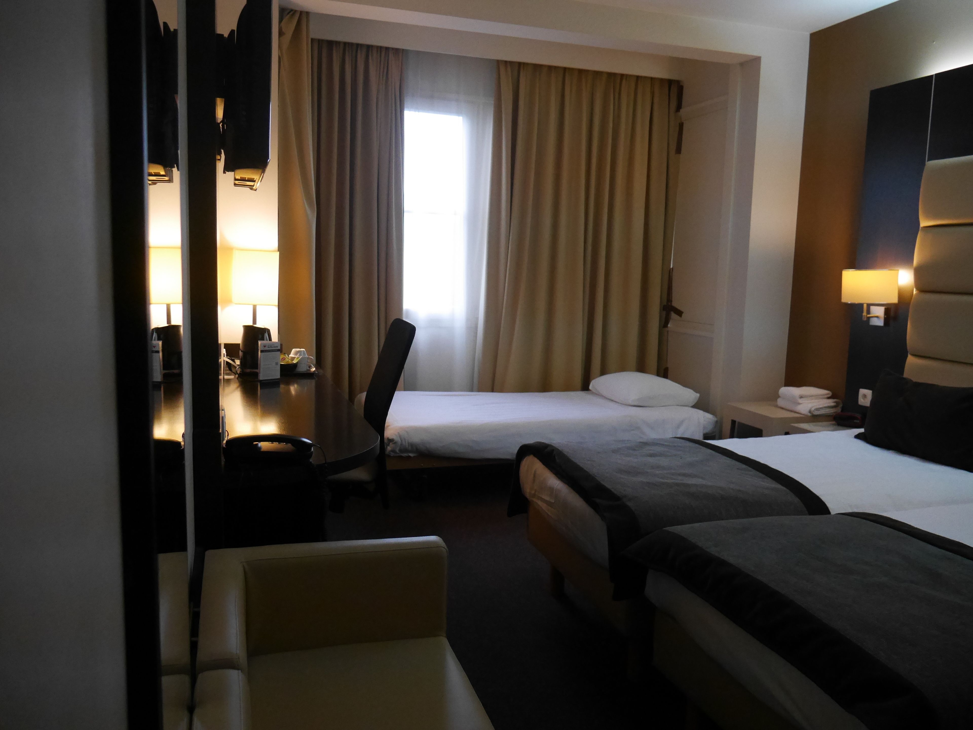 Een hotelkamer met twee bedden, een bureau, een stoel en een lamp.