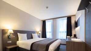 Una habitación de hotel moderna con una cama grande, lámparas de noche, un escritorio con una silla y un televisor de pantalla plana.