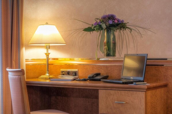 A hotel reception desk with a lamp, a phone, and a laptop. - Hotel Ambassador Bosten (Eupen)