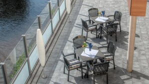 Un espace extérieur aménagé avec des tables et des chaises, offrant une vue sur une rivière.