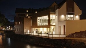 Une maison moderne à deux étages, dotée d’un balcon donnant sur un plan d’eau.