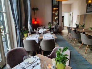 Un restaurante con una larga mesa dispuesta para comer, rodeada de sillas y vistas a la ciudad a través de amplios ventanales.