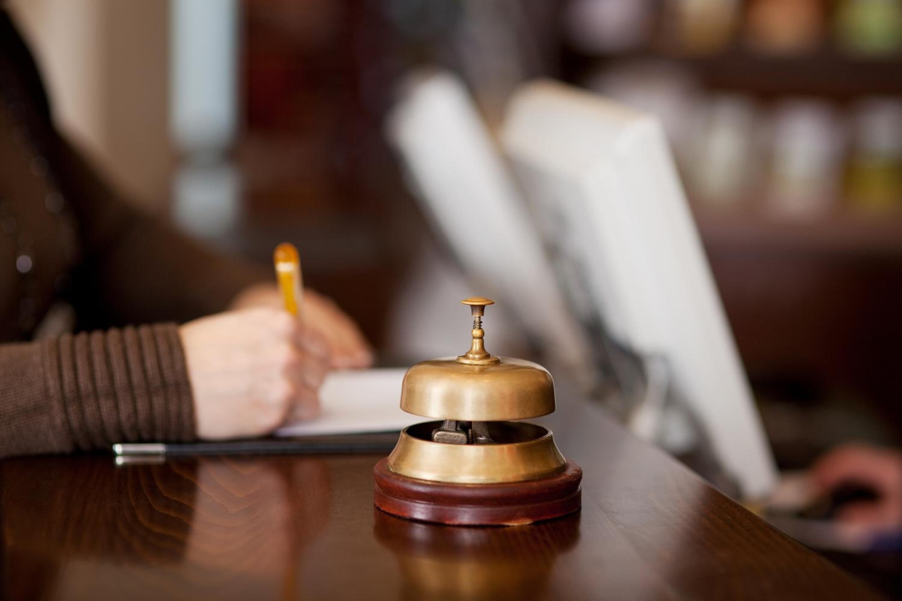 Una campana de bronce sobre un escritorio de madera, probablemente en un hotel u oficina.