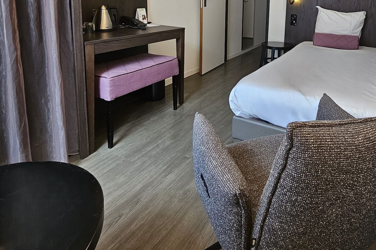 Een hotelkamer met een bed, een bureau, een stoel en een klein tafeltje.