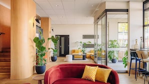 Un interior moderno con un sofá rojo, detalles de madera y plantas en macetas.