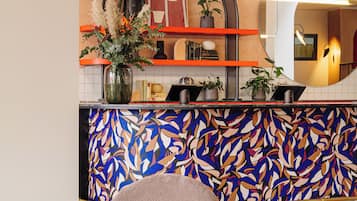 Een moderne receptie met een kleurrijke abstracte wand, een receptiebalie en comfortabele zitplaatsen.