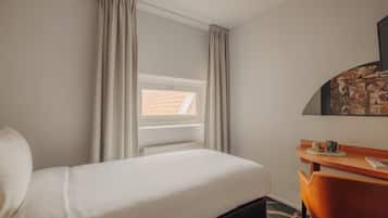 Une chambre d’hôtel avec un lit, un bureau et une fenêtre avec des rideaux.