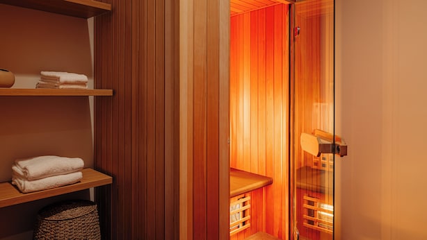 Un sauna con paredes de madera, un banco y estantes con toallas.