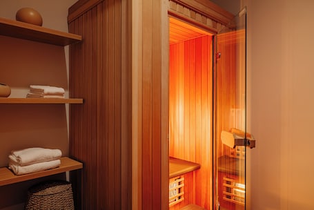 A sauna room with wooden walls, a bench, and shelves with towels.
