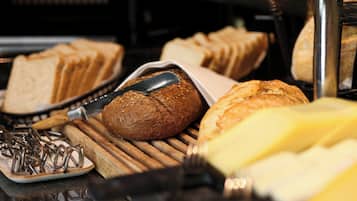 Diverse broden en gebak worden gepresenteerd, waaronder een stokbrood met sesamzaadjes en een rond brood met een goudbruine korst.