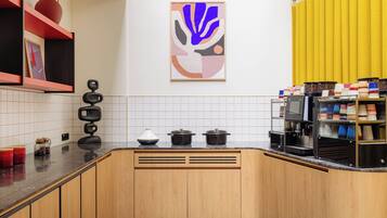 A modern kitchen with wooden cabinets, a coffee machine, and a yellow curtain.