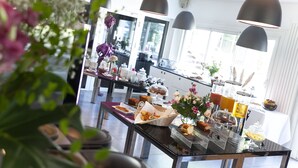 Disposição de buffet com diversos tipos de comida e arranjo floral.