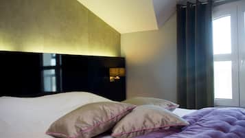 Una habitación de hotel con una cama grande, un cabecero y un ventanal con cortinas.