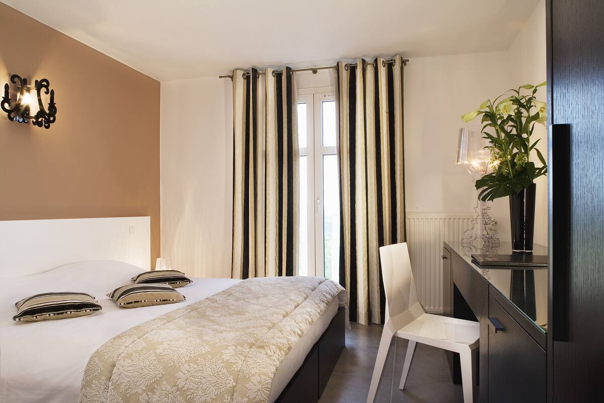 Ein Hotelzimmer mit Bett, Stuhl, Schreibtisch und einer Zimmerpflanze.