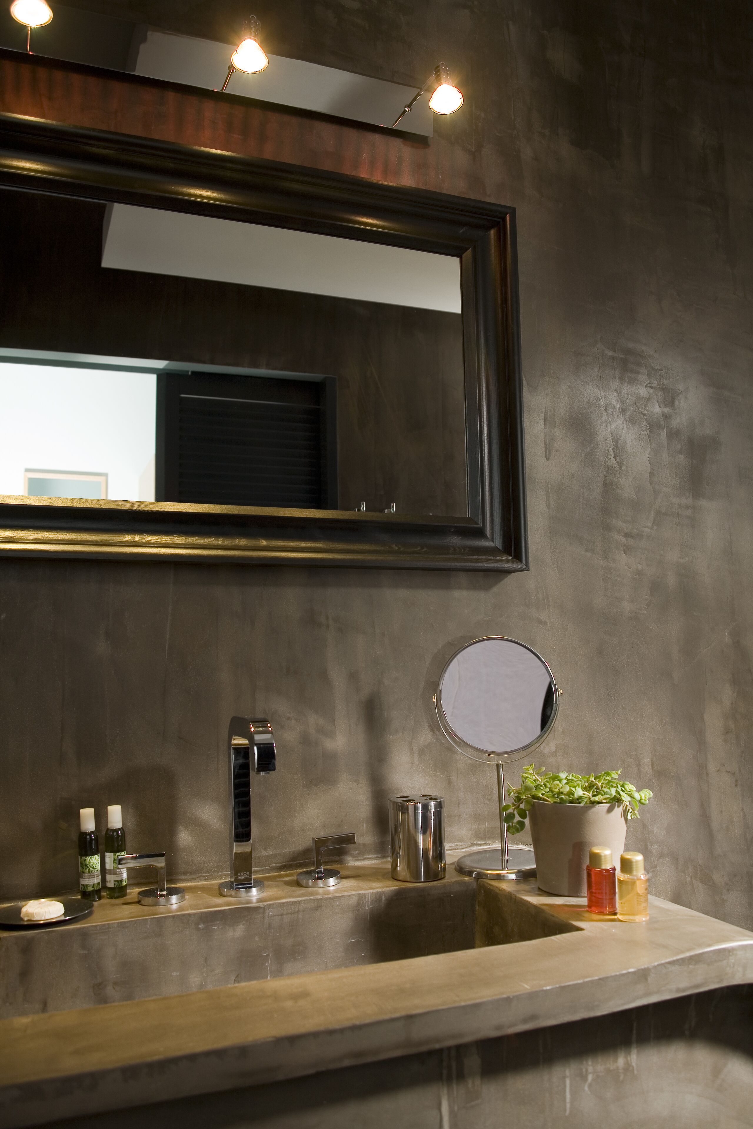 Un baño con un espejo grande, un lavabo y una planta en maceta.