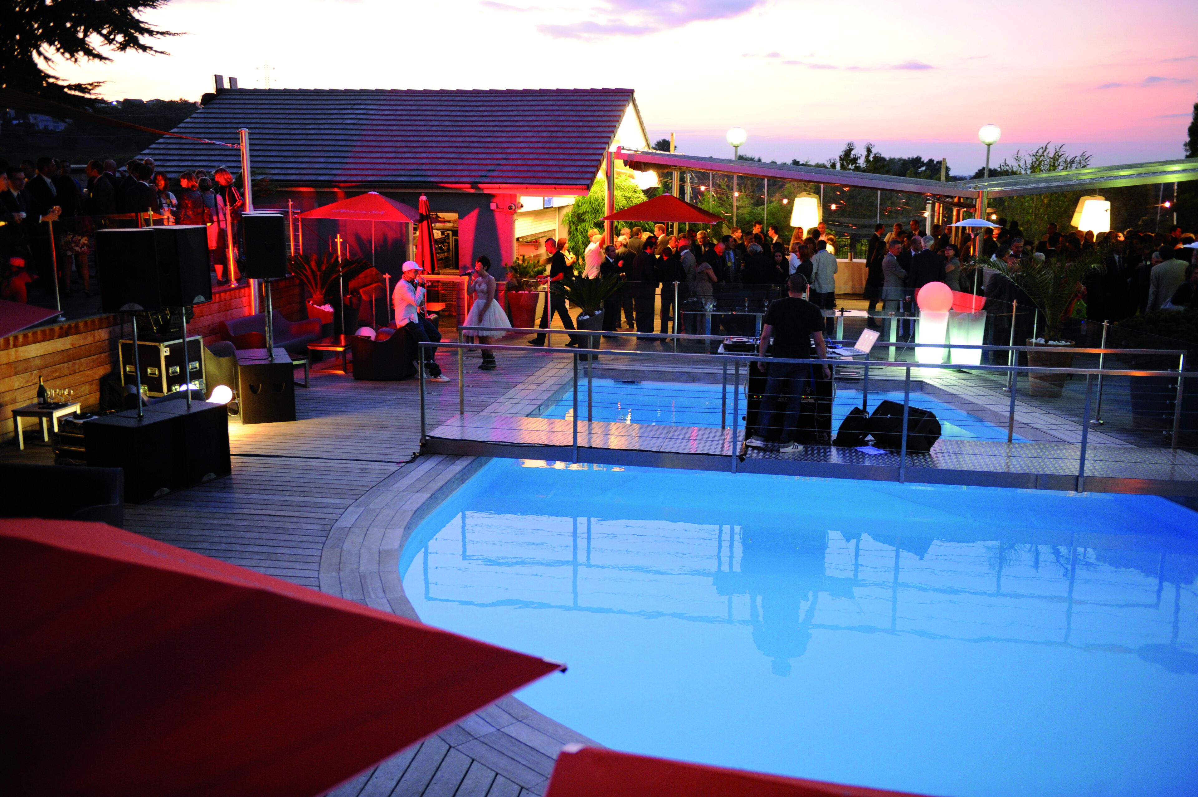 Un área de piscina con terraza de madera, sillones de descanso y sombrillas.