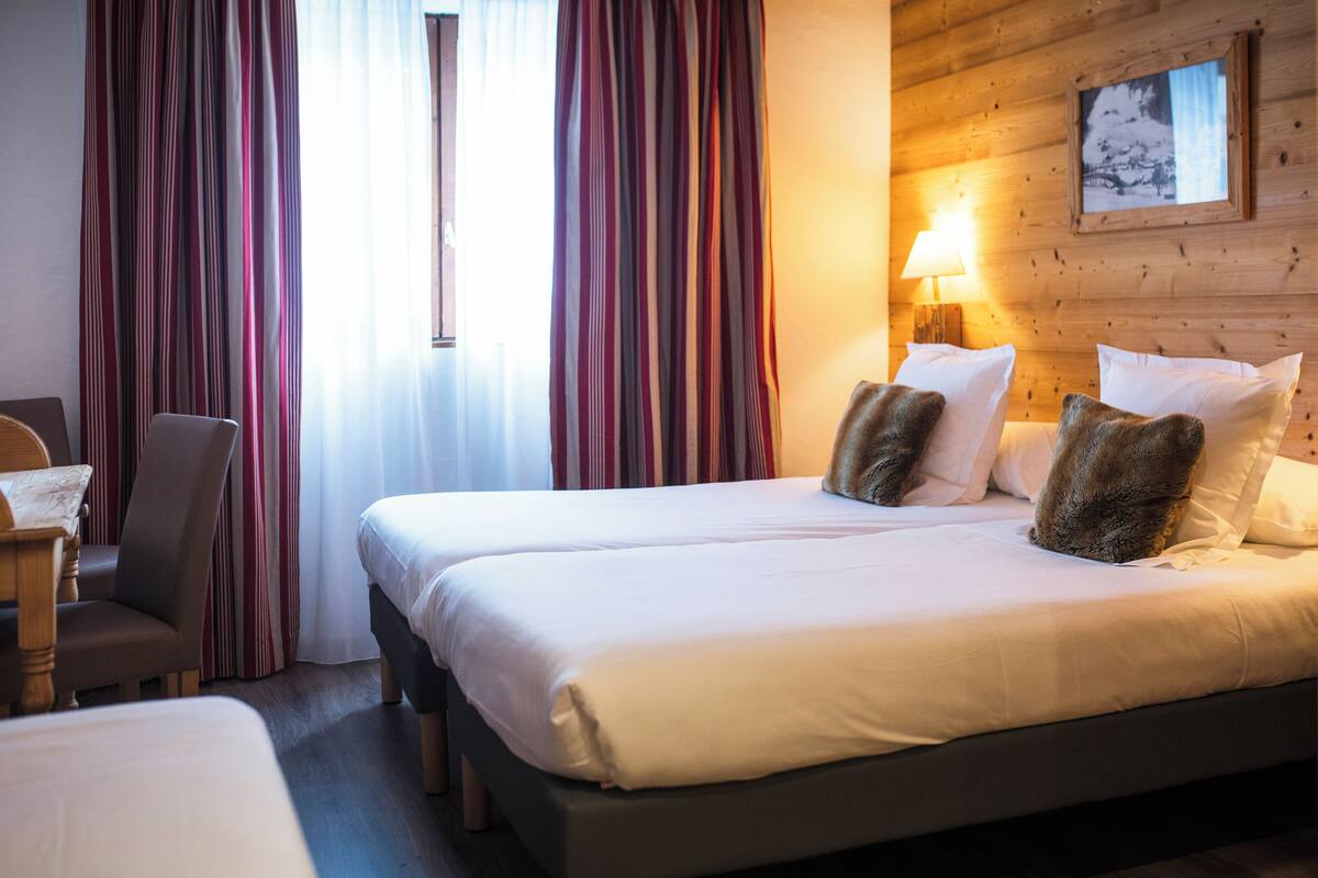 A hotel room with a large bed, a chair, and a lamp.