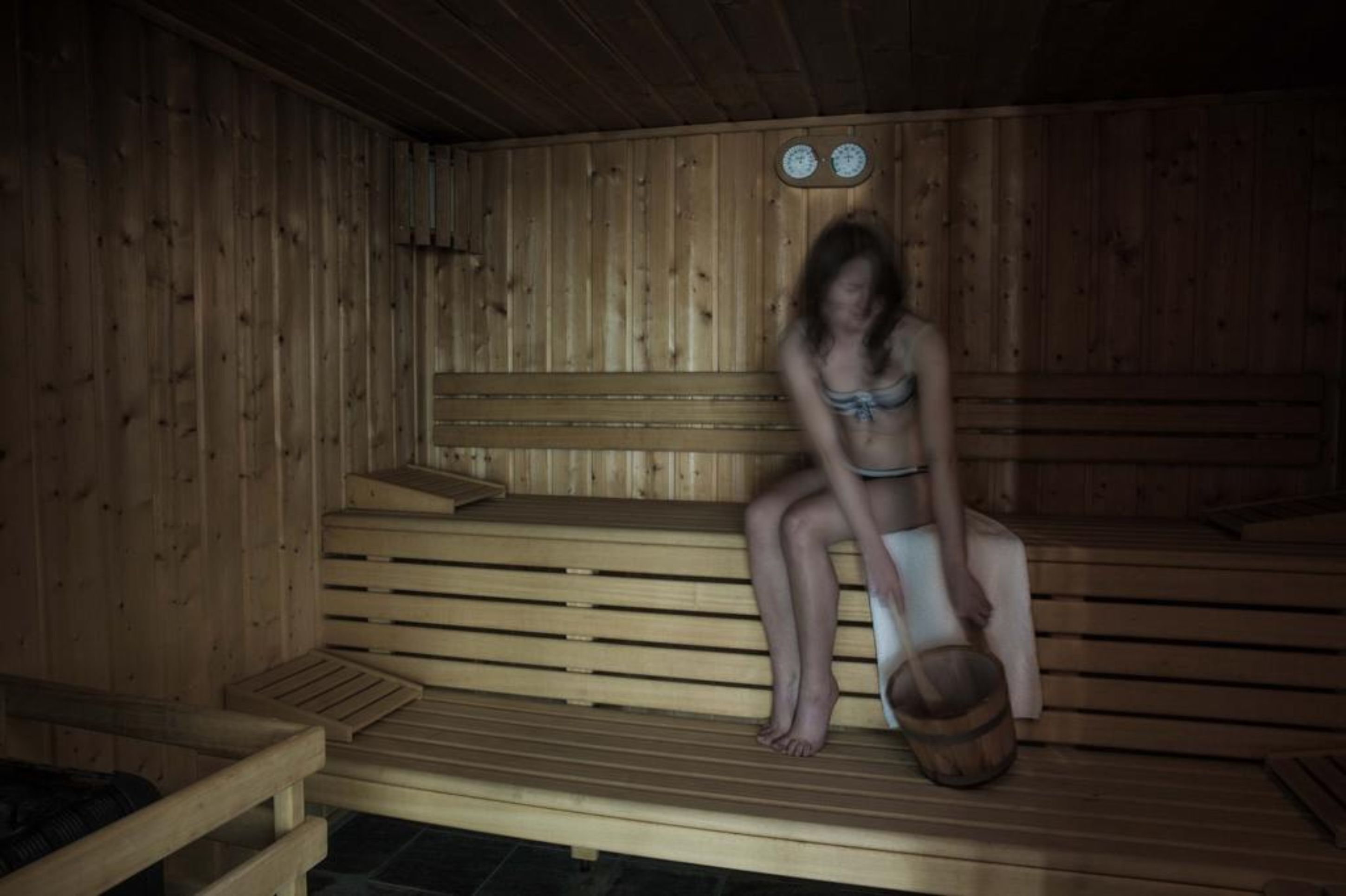 Un sauna en bois avec des bancs et un seau en bois.