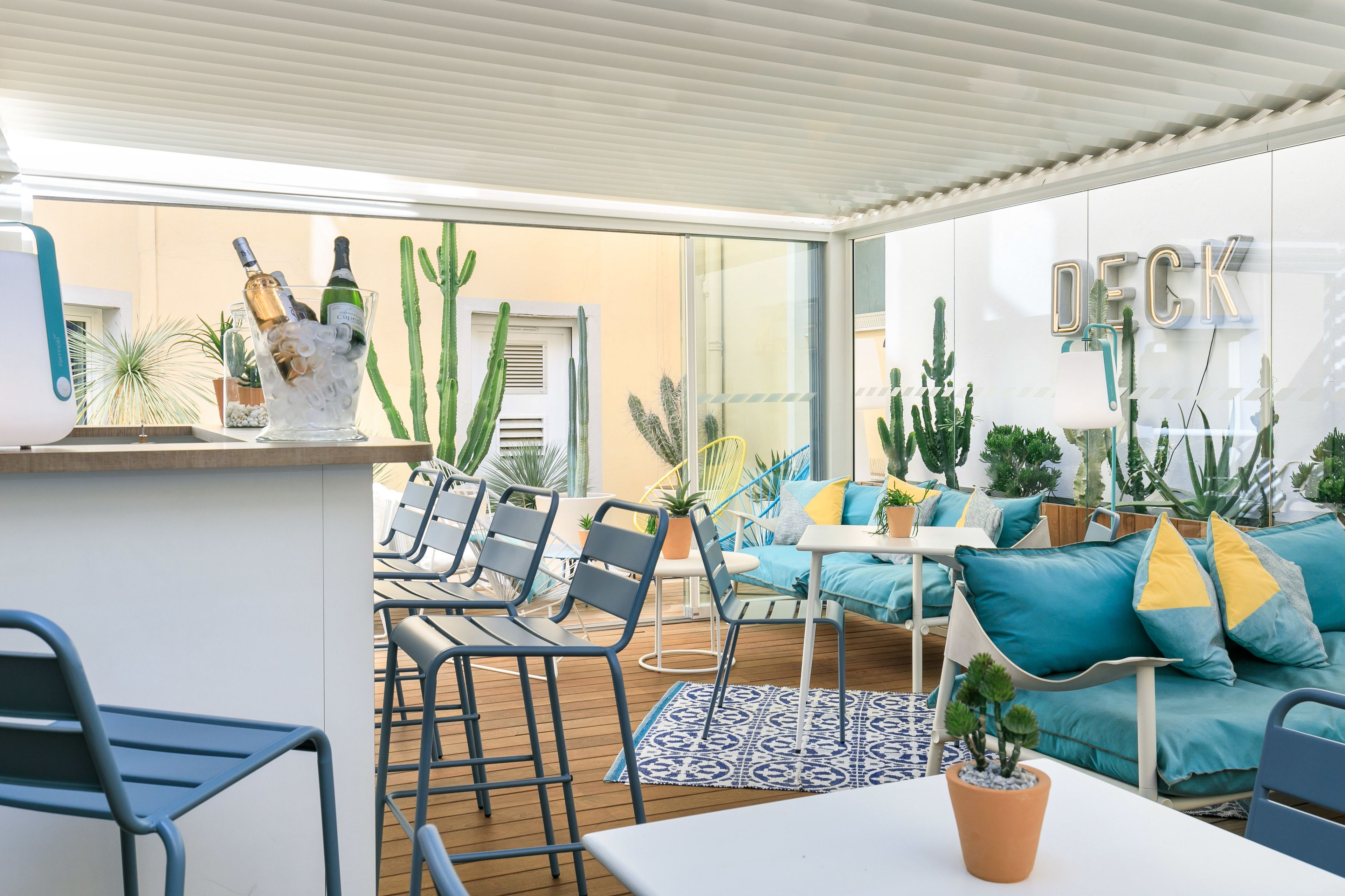 A modern outdoor patio area with a bar, seating, and potted plants.