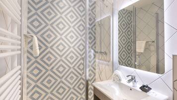 A modern bathroom with a geometric patterned shower wall, a large mirror, and a white sink.