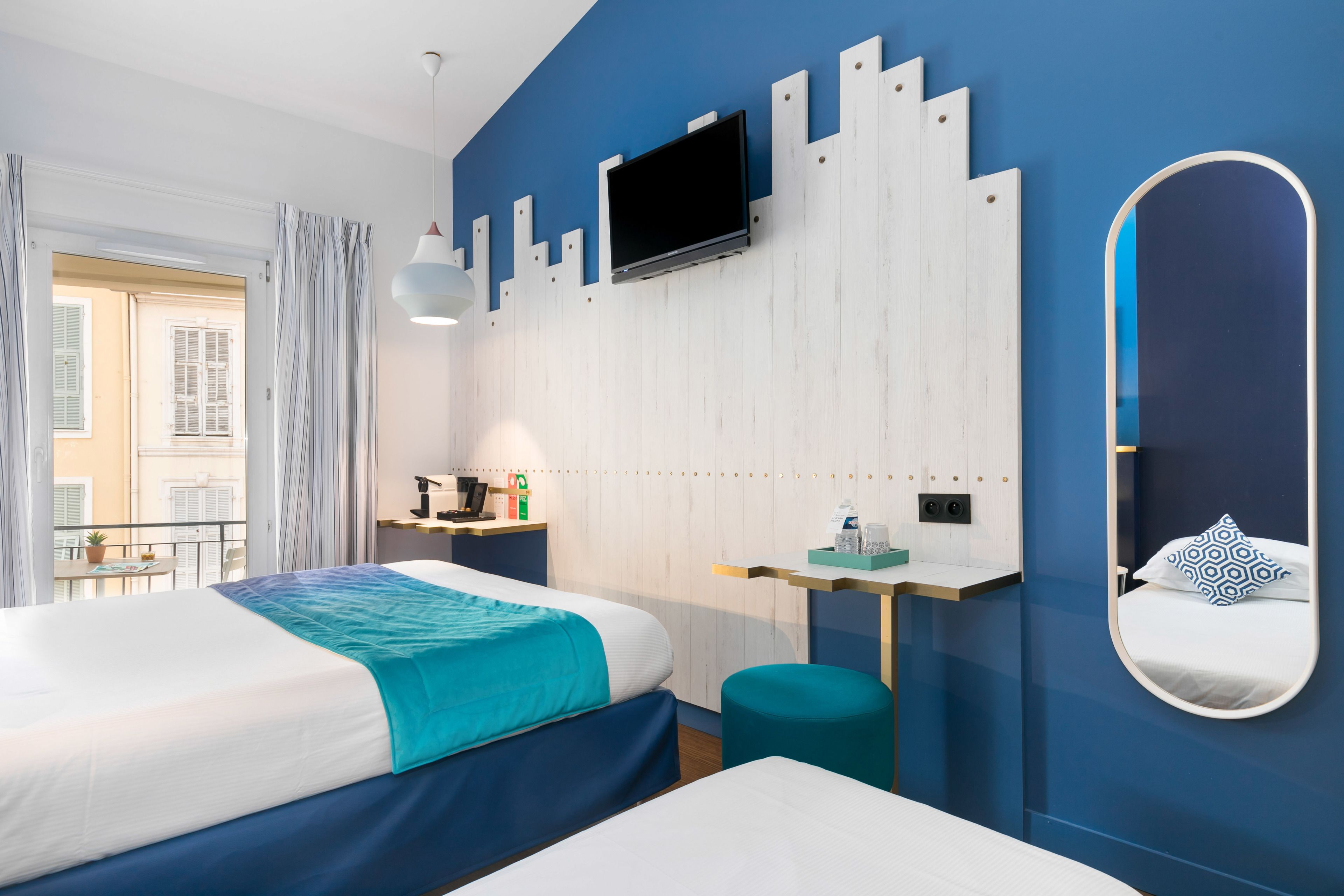 A modern hotel room with a large bed, a desk, a TV, and a mirror.