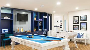 A pool table in a room with a blue and white color scheme, a television mounted on the wall, and a seating area with a white chair and a couch.