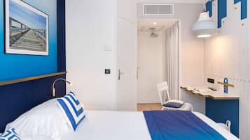 Ein Hotelzimmer mit Bett, Schreibtisch, Stuhl, Dusche und Badezimmer.
