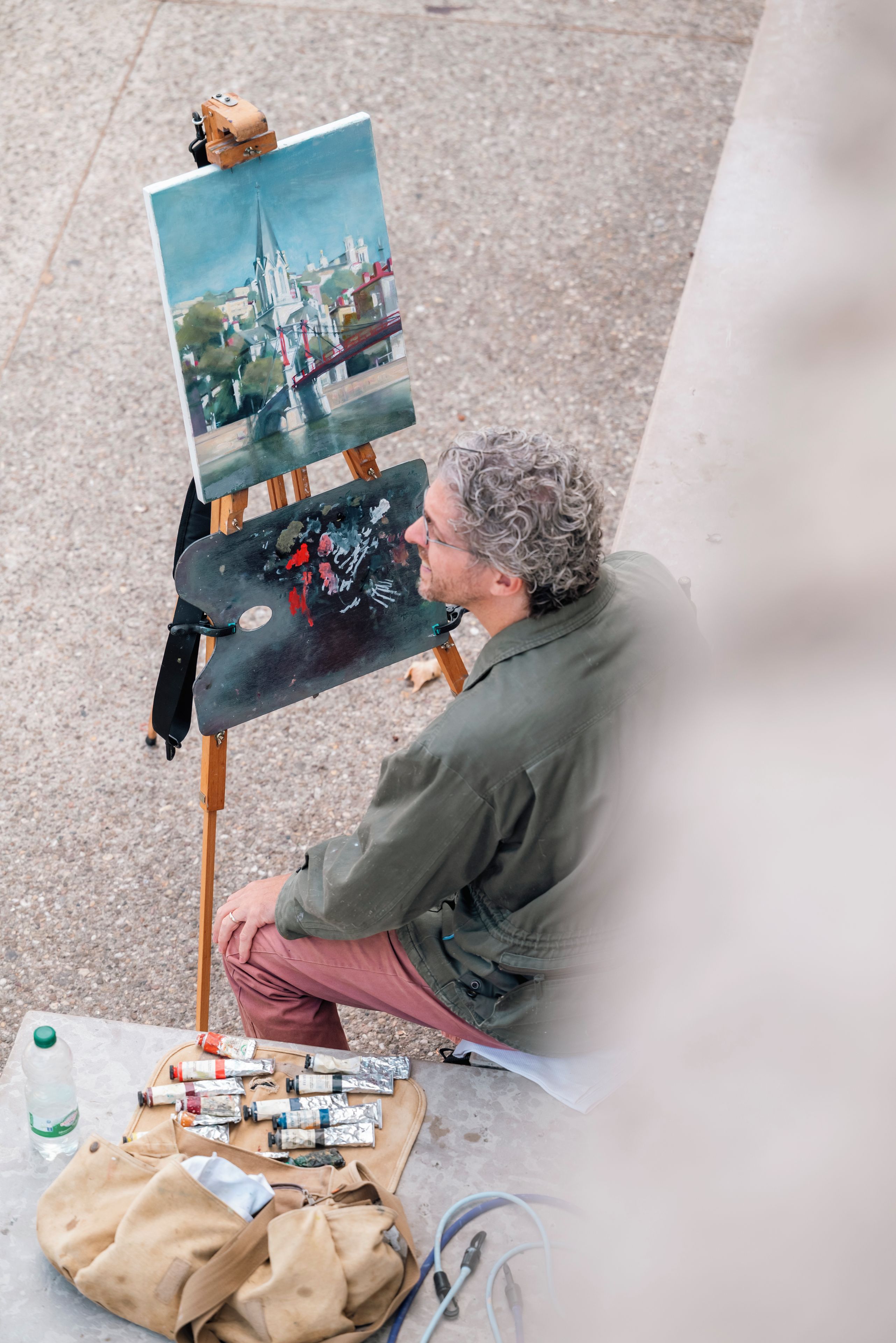 Un artista pintando un paisaje al aire libre sobre un caballete.