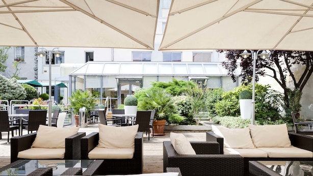 An outdoor seating area with wicker furniture and umbrellas. - Hotel Charlemagne By HappyCulture  (Lyon)