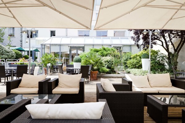 Un área de estar al aire libre con muebles de mimbre y sombrillas.