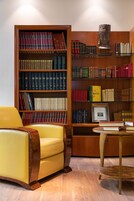 Una biblioteca con scaffali, una poltrona gialla e un tavolo in legno.